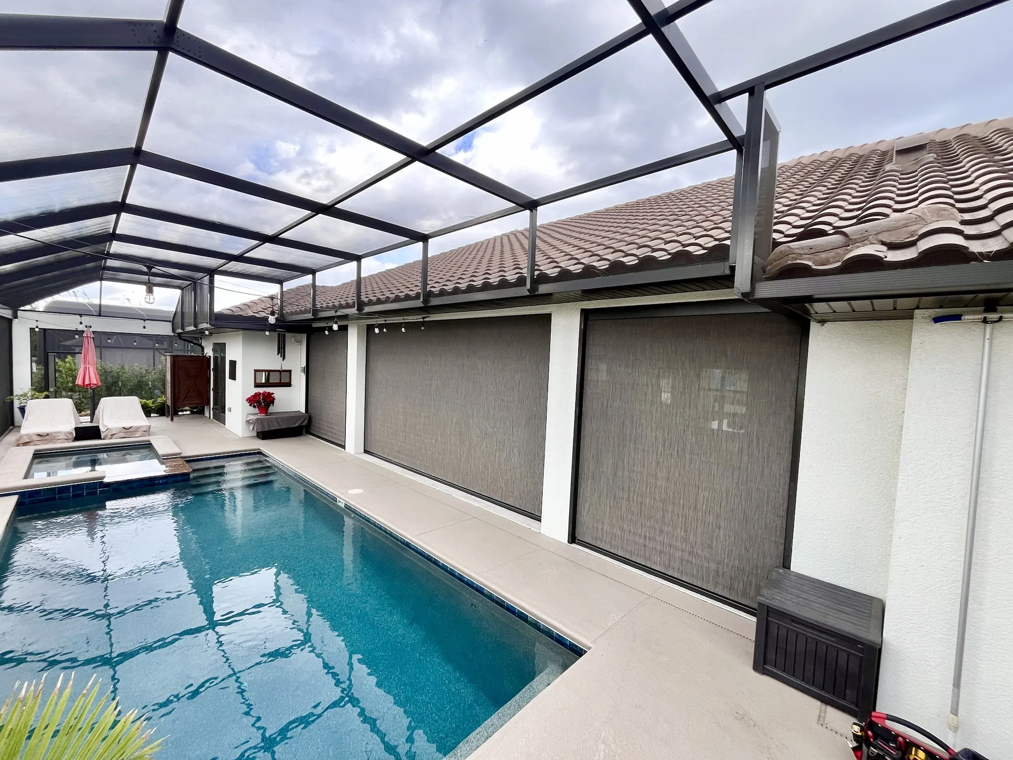 Motorized exterior shades enclosing a screened pool lanai