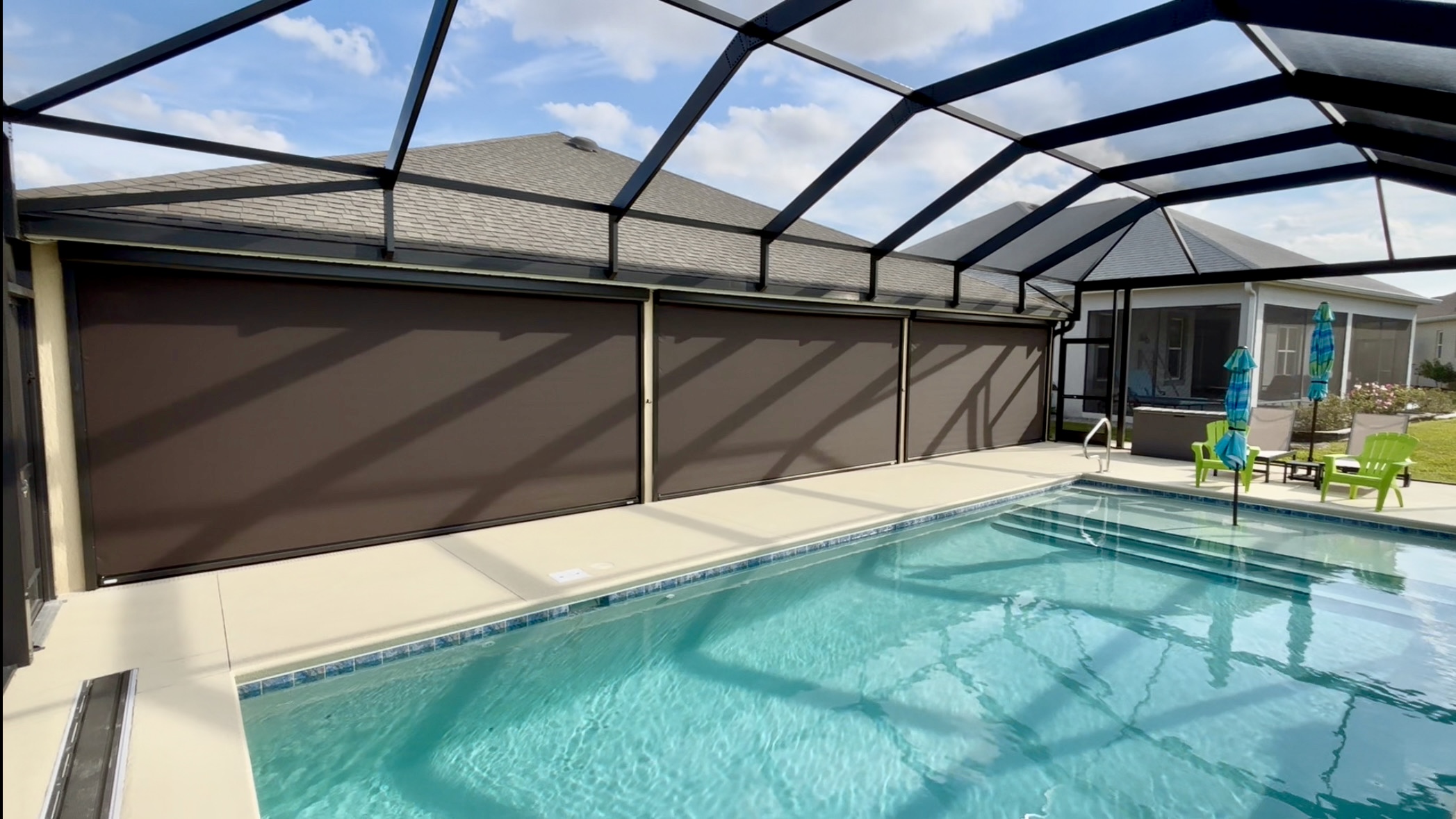 exterior dim out motorized shade for patio lanai overlooking pool and enclosed birdcage