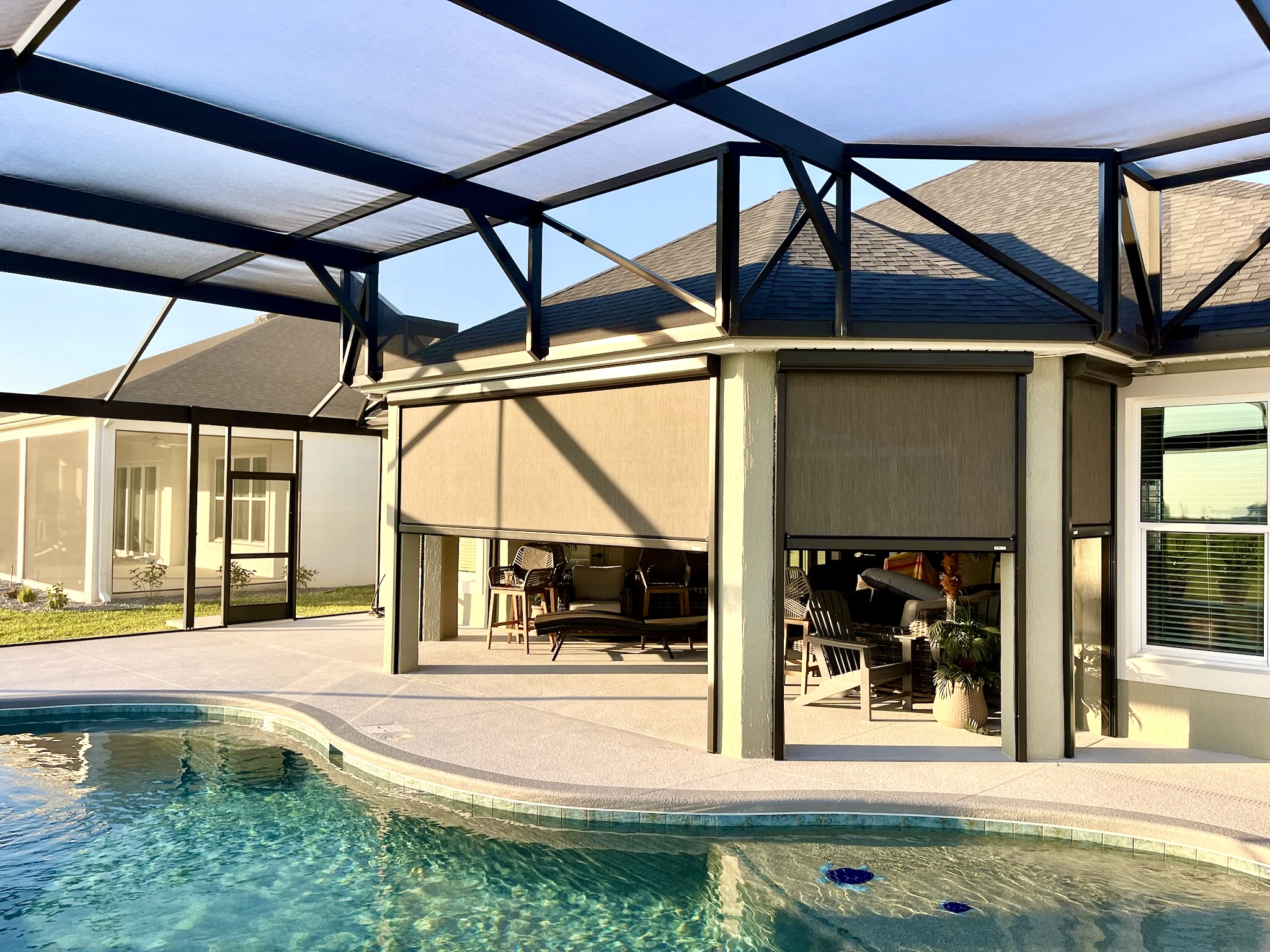Exterior motorized shade for patio lanai overlooking pool in enclosed birdcage